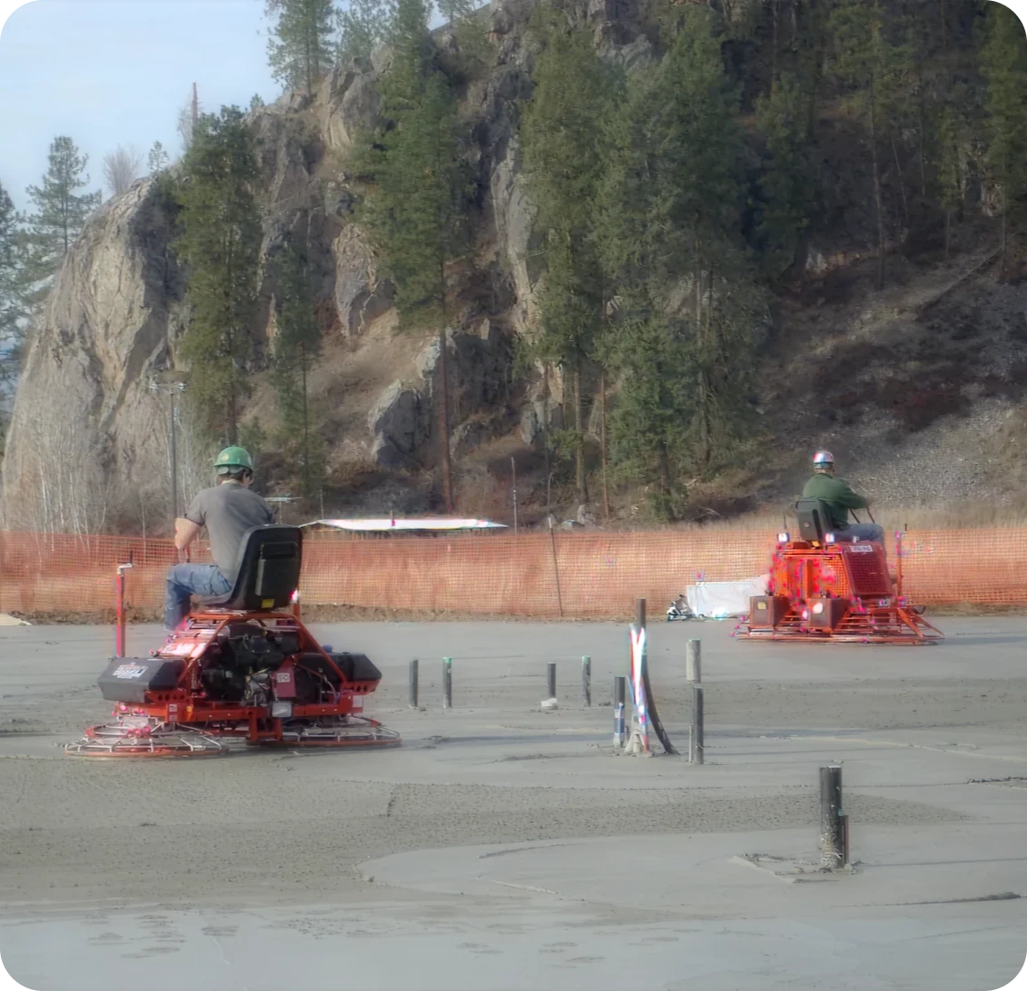 Construction workers using power trowels on concrete